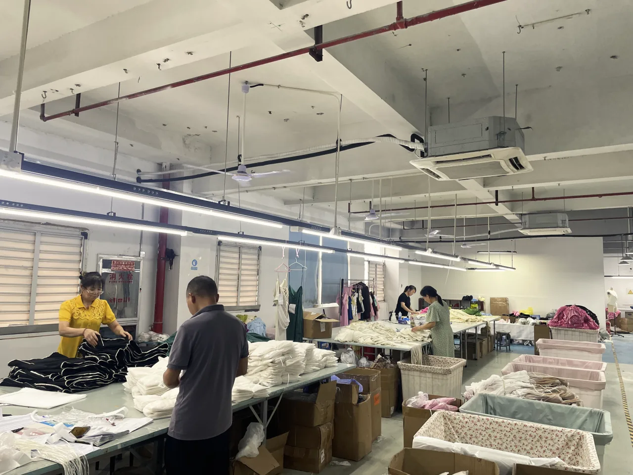 Workers folding and stacking garments in the packing area.
