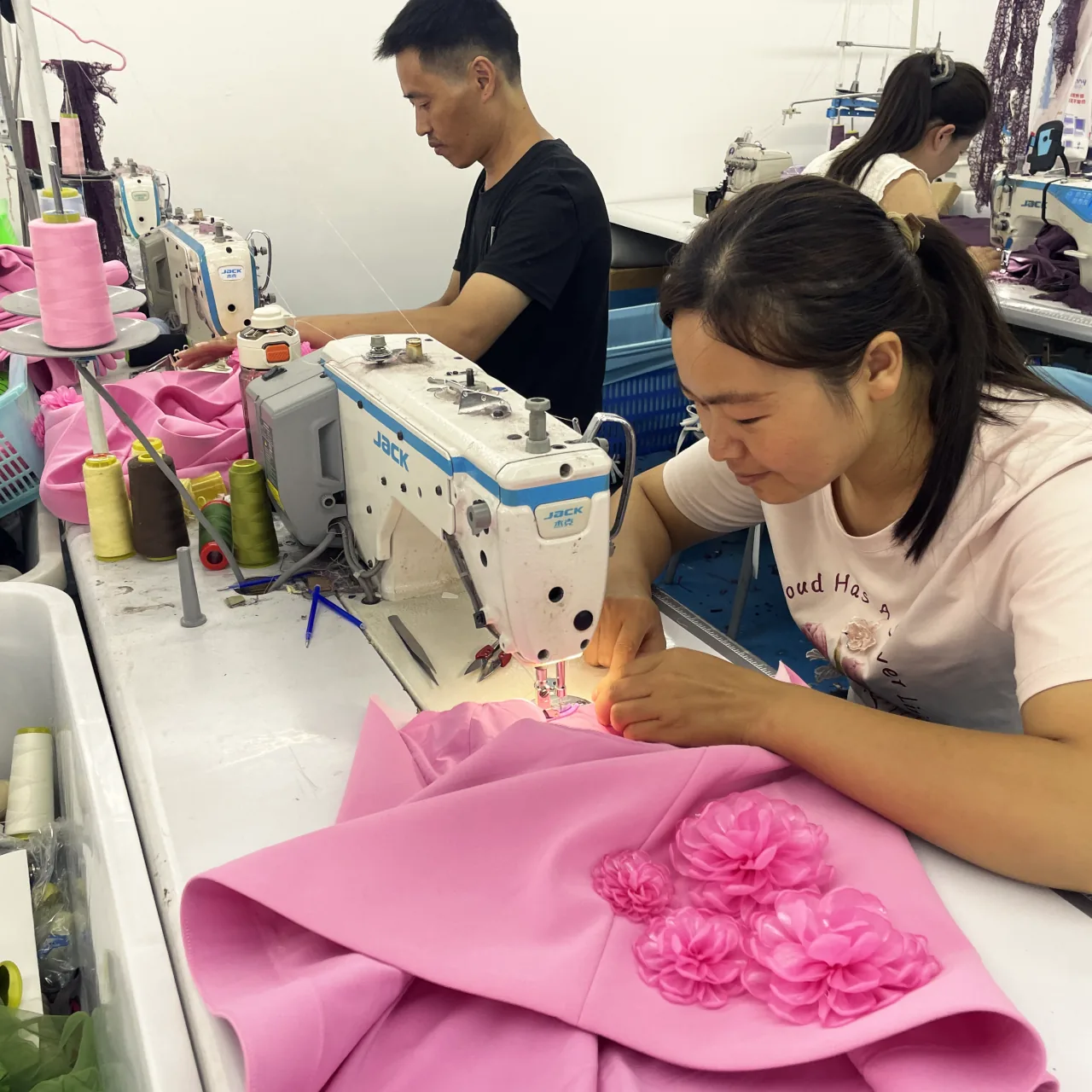 A machinist sewing a pink panel decorated with fabric flowers.